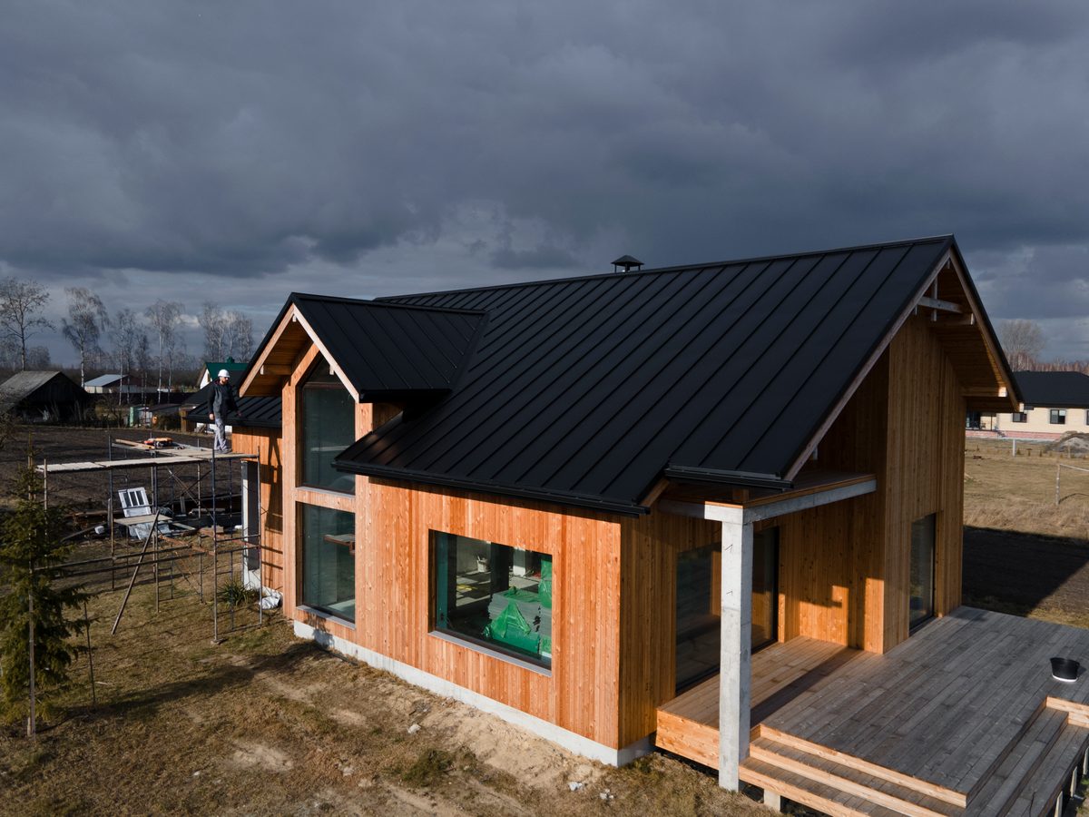 Chantier d'une maison ossature bois plain-pied avec bardage bois naturel et toiture métallique noire